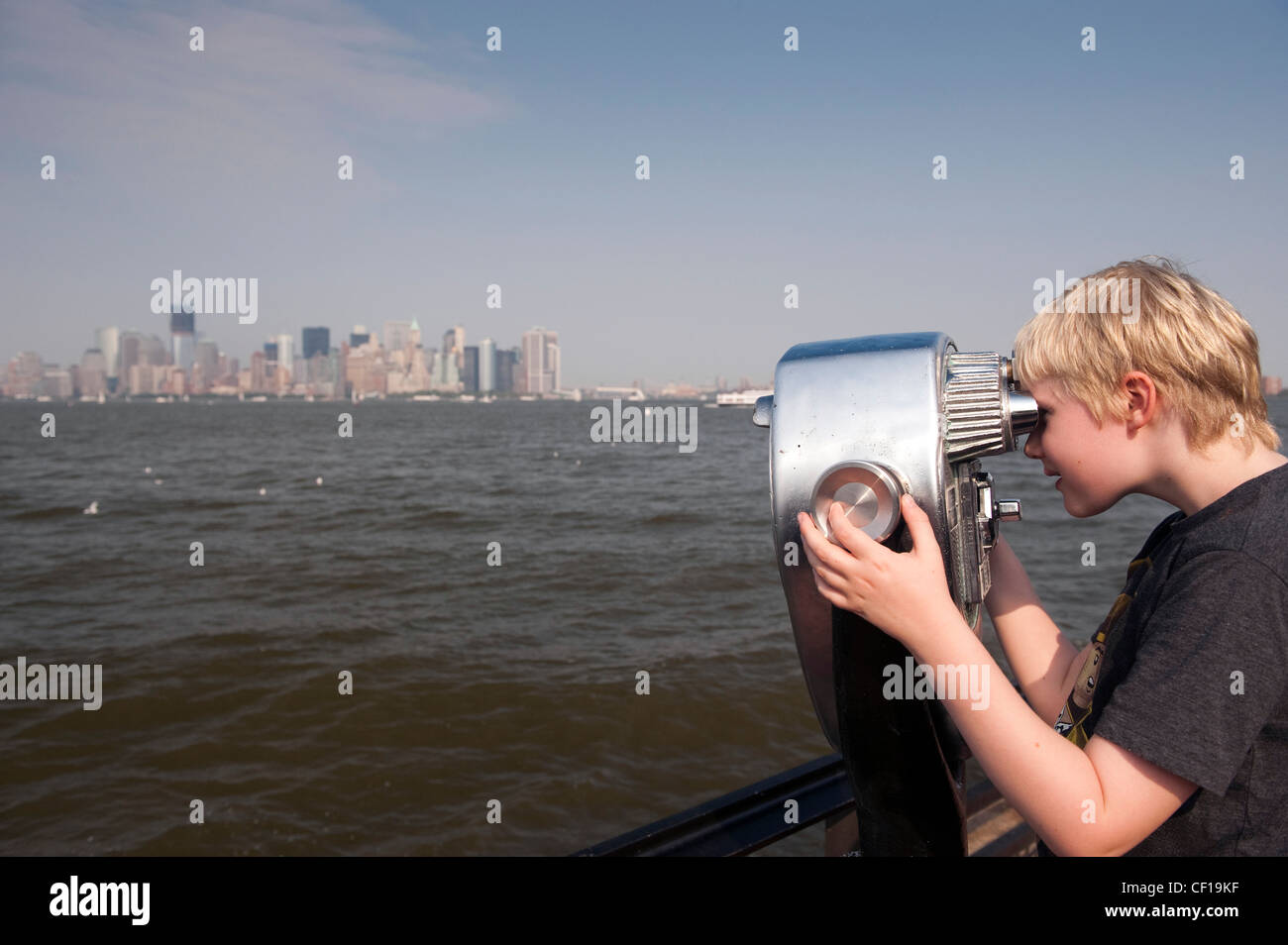 Jeune garçon à l'aide de pièces chromées jumelles pour voir l'horizon de New York. Banque D'Images