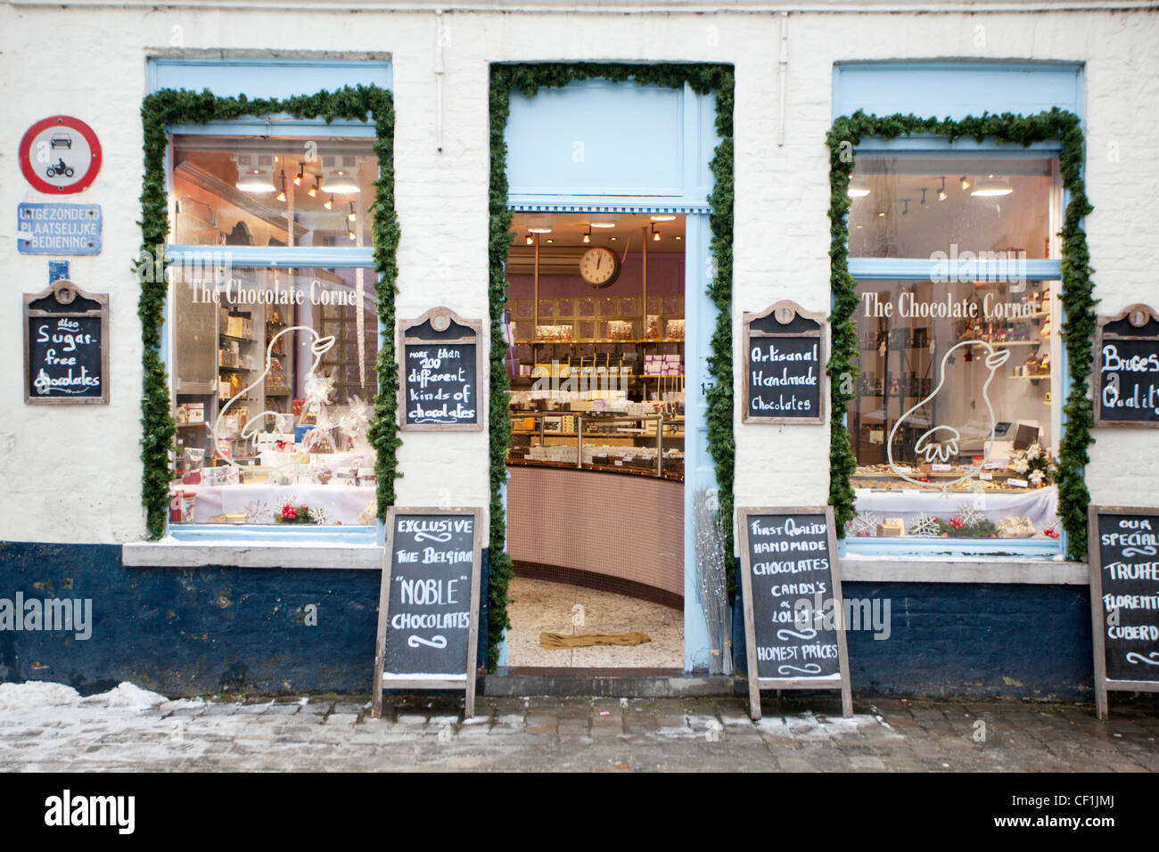 Vue de l'avant d'une boutique de chocolat à Bruges avec menu chalk boards disposés sur les cailloux couverts de neige Banque D'Images