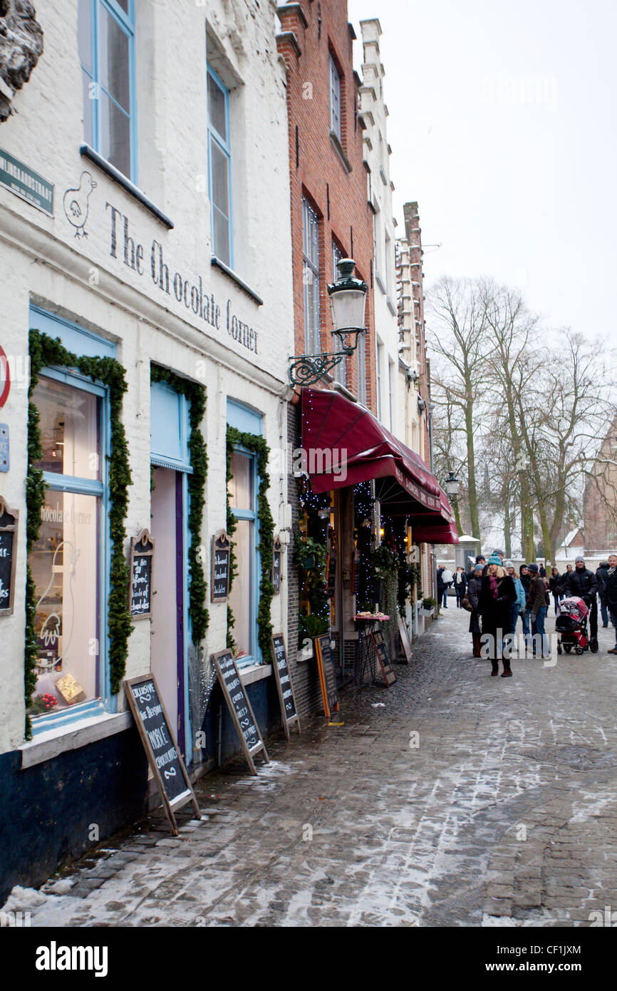 Vue de l'avant d'une boutique de chocolat à Bruges avec menu chalk boards disposés sur les cailloux couverts de neige Banque D'Images