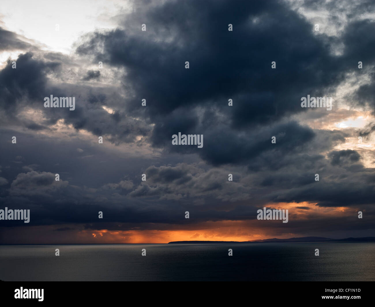 Voyant orange briser les nuages de tempête sur la mer d'Irlande à partir de Llanfair. Banque D'Images