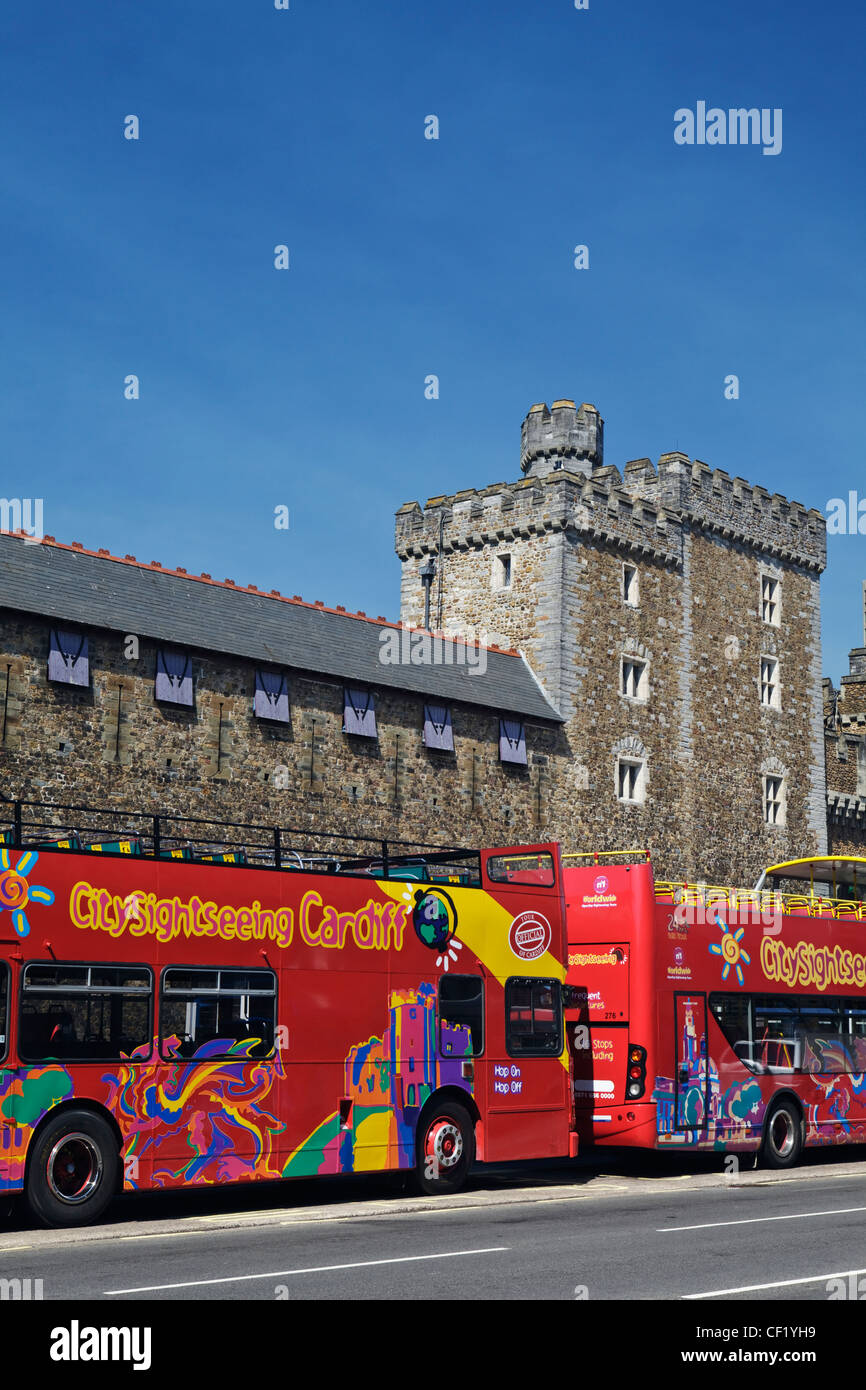Ouvert double decker bus touristiques à visiter à l'extérieur le château de Cardiff. Banque D'Images