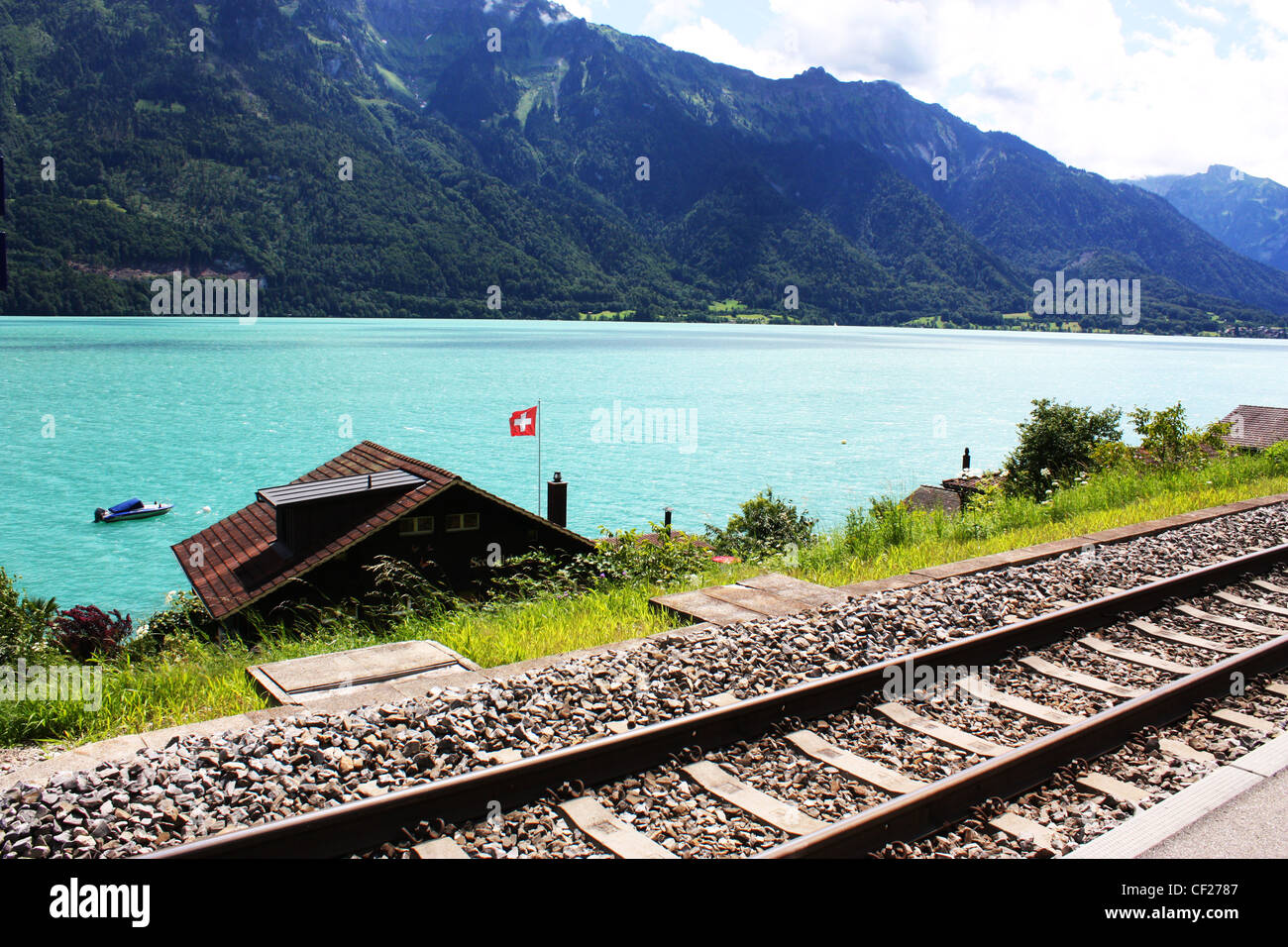 La voie de chemin de fer suisse avec maisons, lac et montagne Banque D'Images