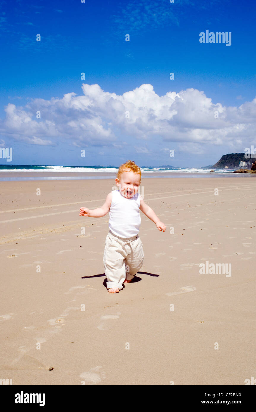 Bebe Male Aux Cheveux Blonds Portant Une Veste Blanche Et Un Pantalon Beige Marcher Le Long De La Plage Smiling Photo Stock Alamy