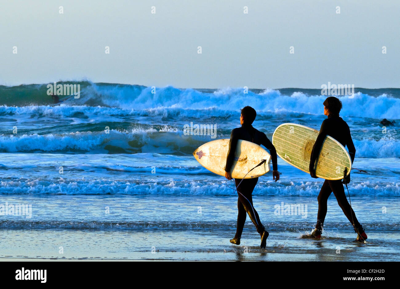 Balades avec leurs planches de surf vers la mer à Towans Gwithian. Banque D'Images