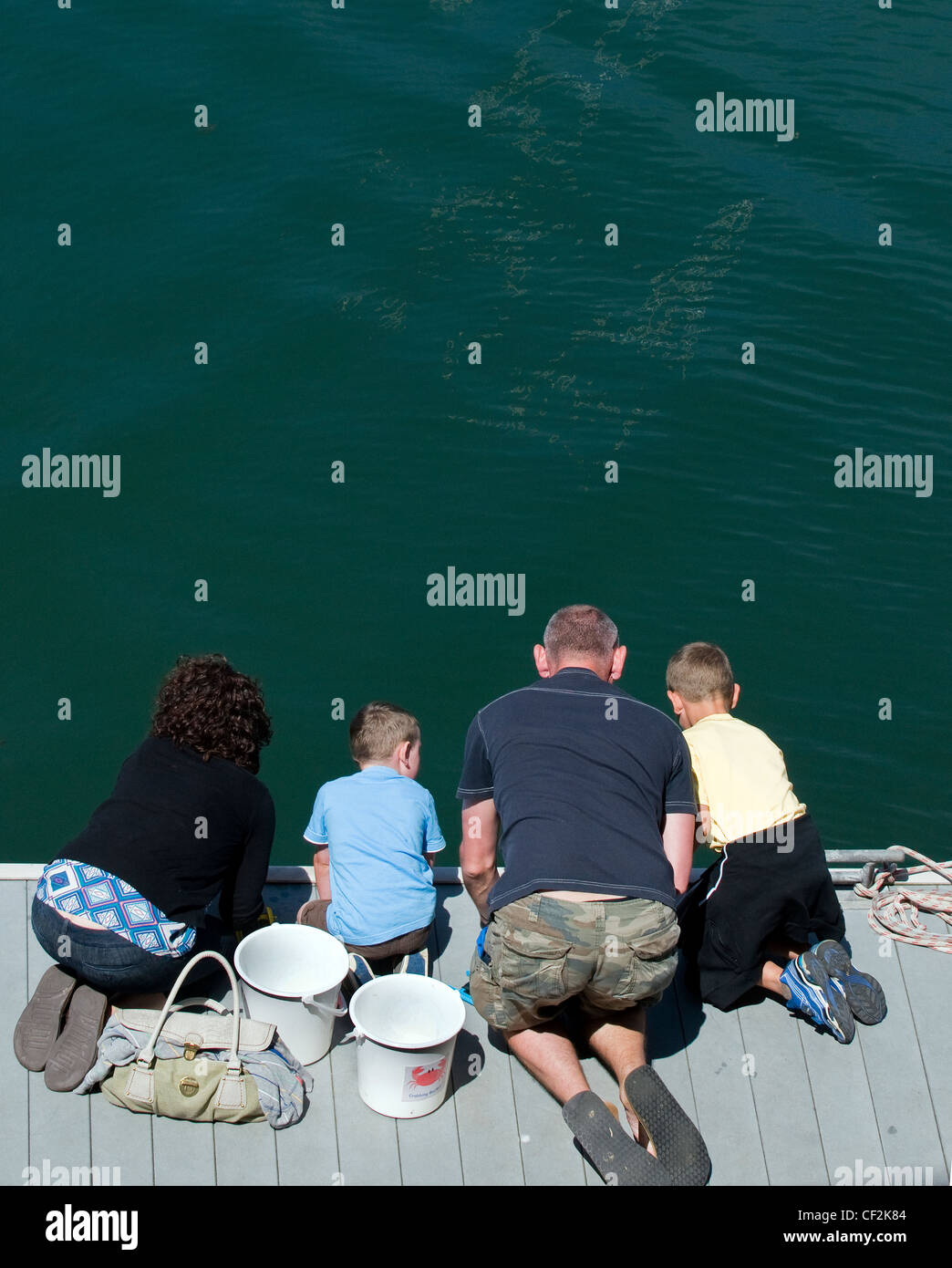 Une famille à genoux sur une jetée de pêche de crabes de Falmouth. Banque D'Images