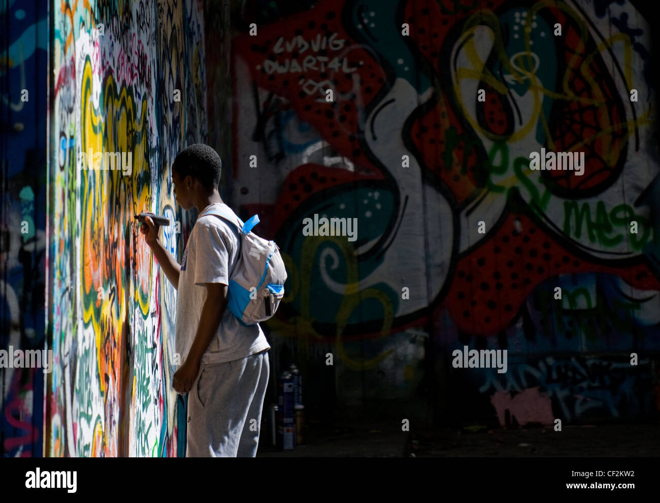 Un adolescent écrit sur un mur recouvert de graffitis. Banque D'Images