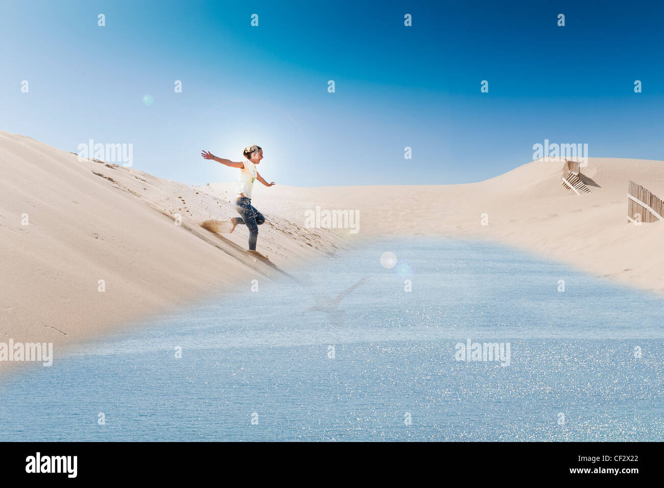 Une jeune femme glisse sur un conseil sur la Punta Paloma dunes de sable dans l'eau ; Tarifa Cadiz Andalousie Espagne Banque D'Images