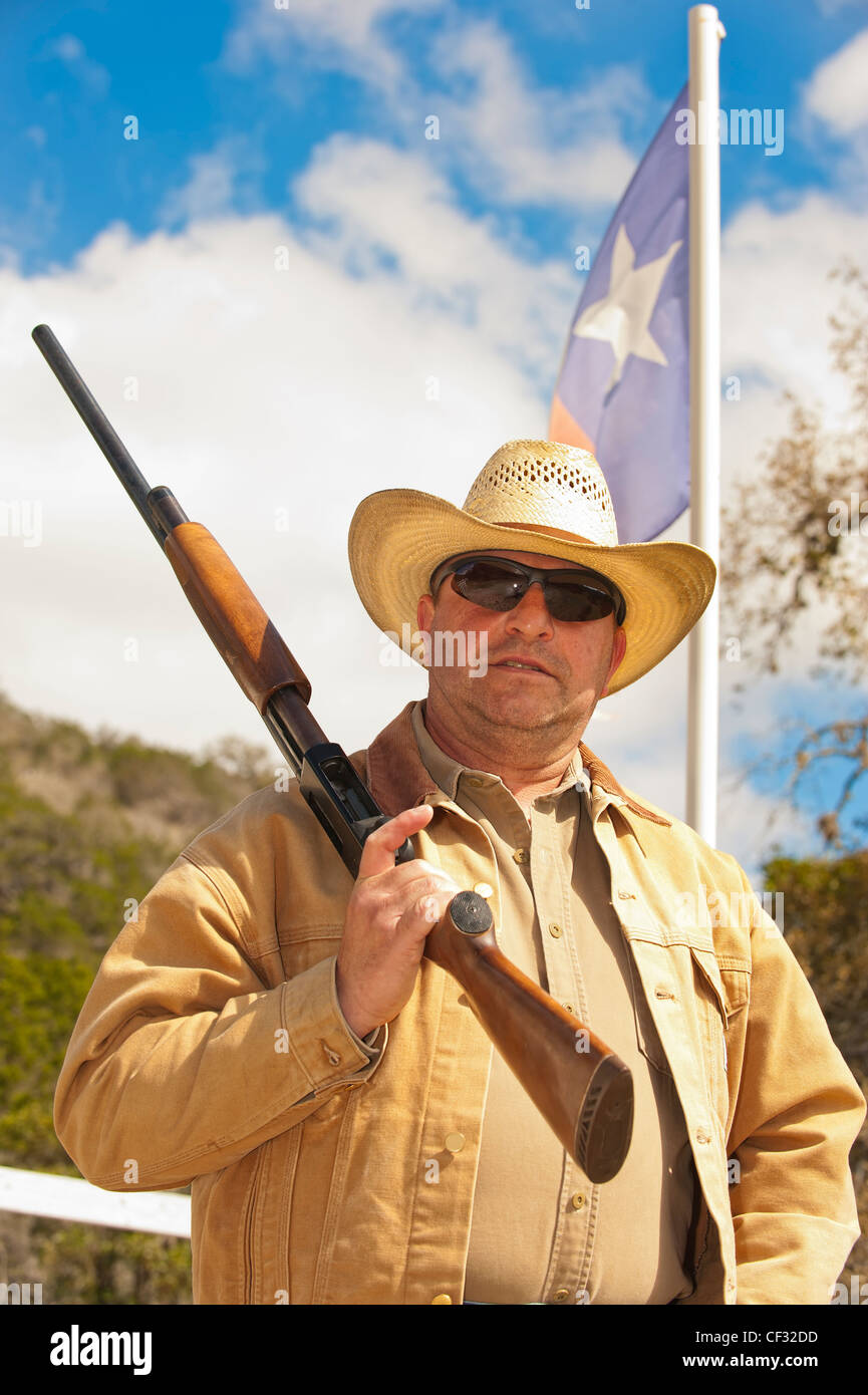Cowboy d'âge moyen avec arme à feu en face du Texas flag Banque D'Images