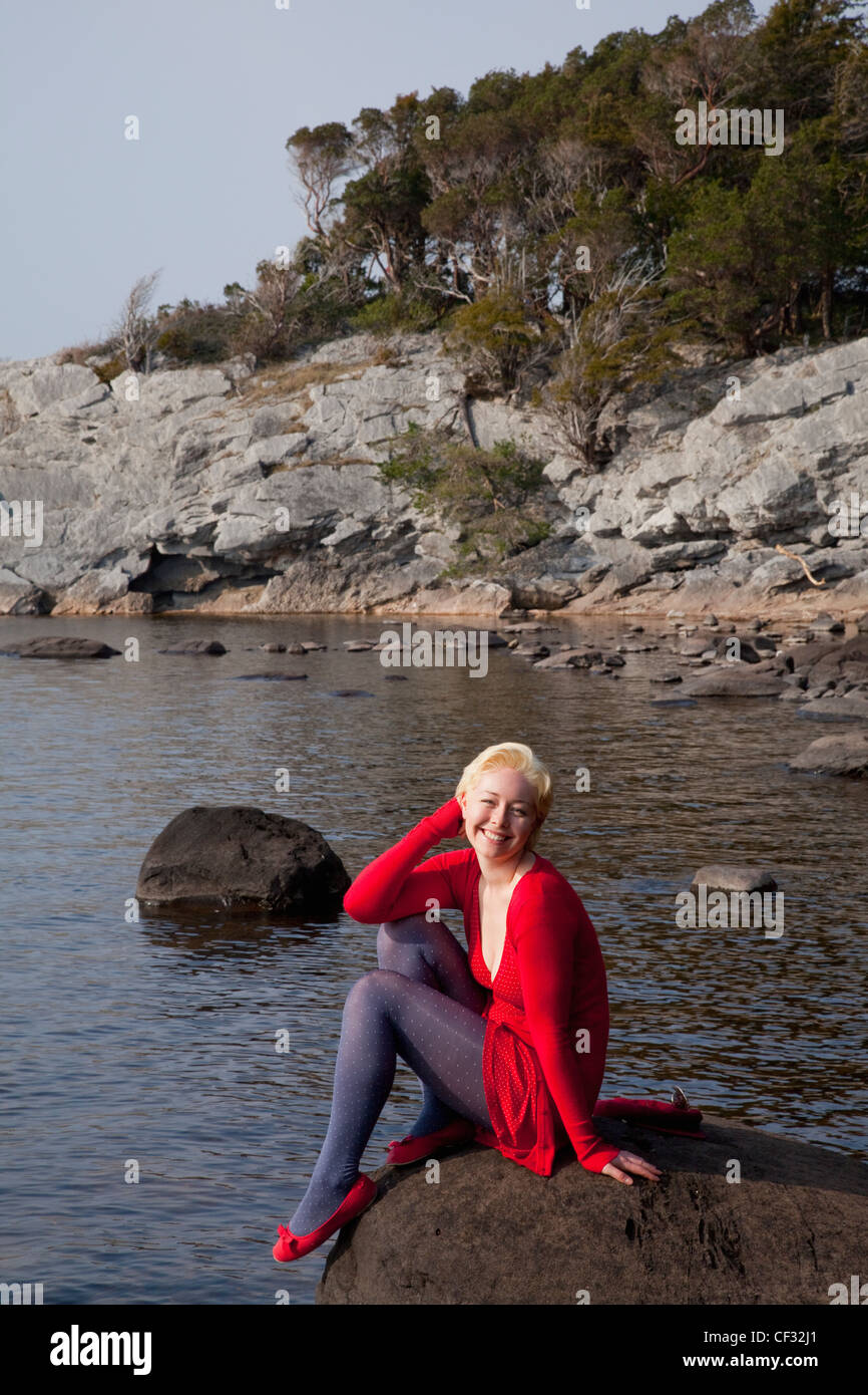 Une jeune femme est assise sur un gros rocher sur Muckross Lake Killarney, County Kerry Ireland Banque D'Images