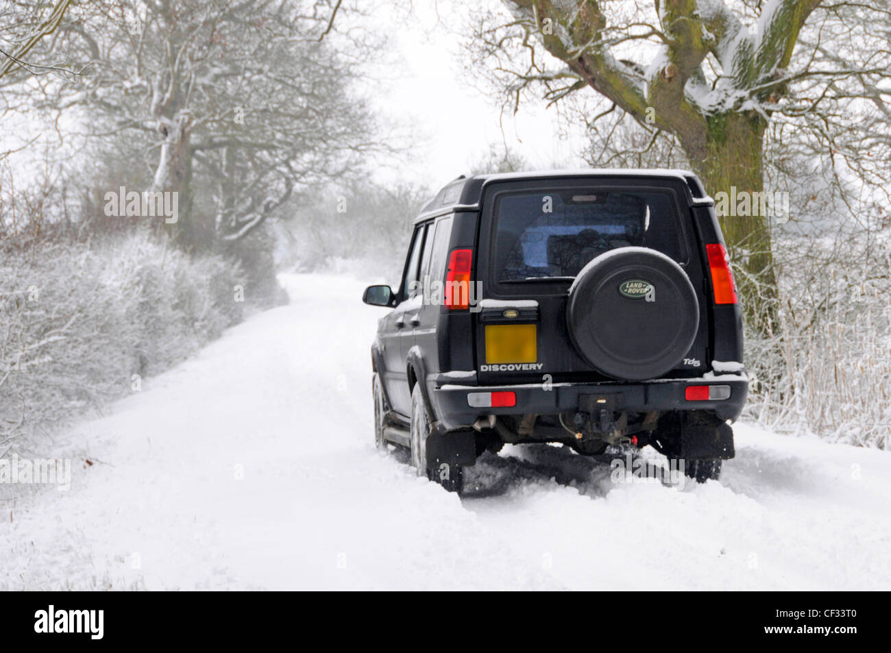 Land Rover Discovery en roulant le long de la neige a couvert country lane (obscurcie, la plaque constructeur et concessionnaire nom supprimé) Banque D'Images