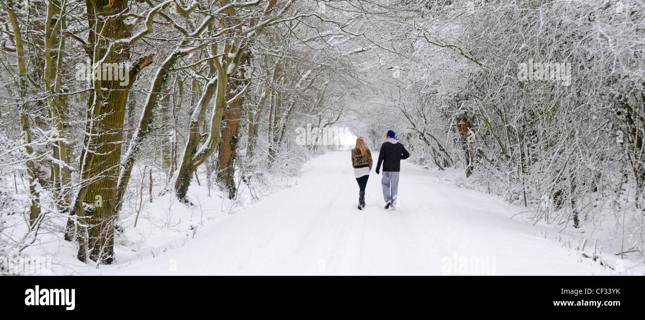 Jeune couple en train de marcher le long de chemin de campagne après les fortes chutes de neige Banque D'Images