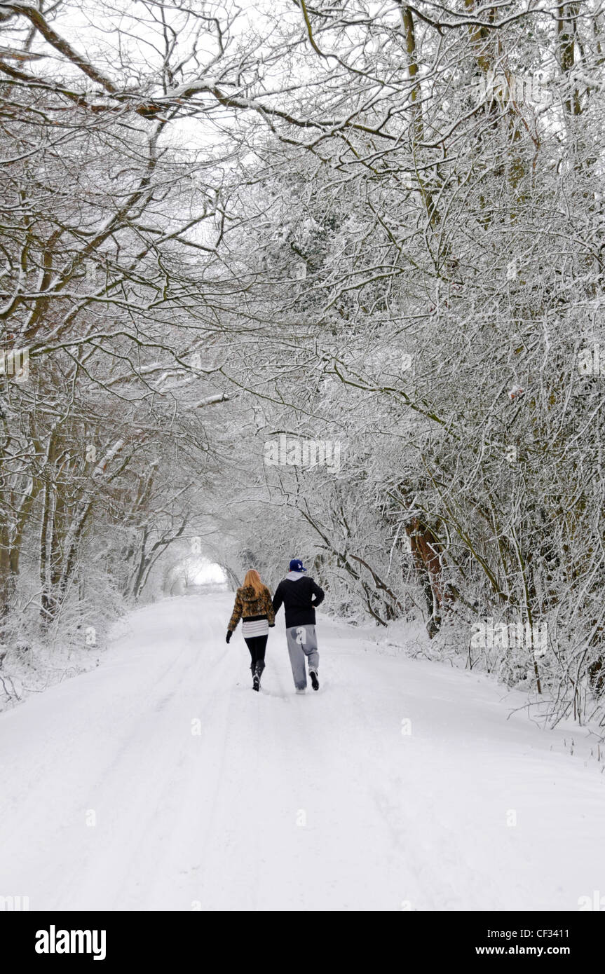 Jeune couple marche main dans la main le long de chemin de campagne après les fortes chutes de neige Banque D'Images