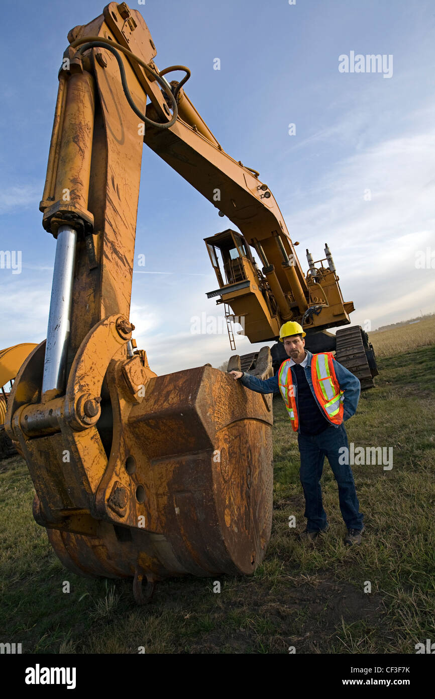 Opérateur d'équipement lourd debout à côté de l'excavation de la machine. Banque D'Images