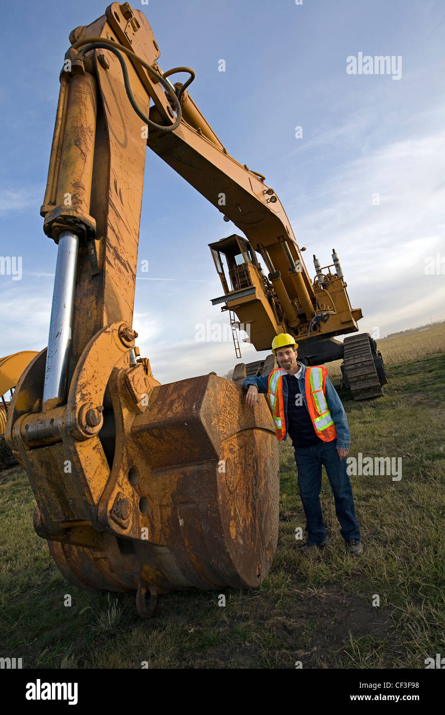 Opérateur d'équipement lourd debout à côté de l'excavation de la machine. Banque D'Images