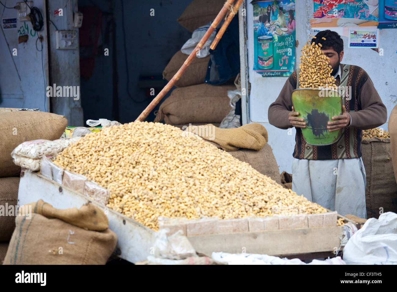 Vendeur dépose de l'écrou de coquilles lâche des arachides, Islamabad, Pakistan Banque D'Images