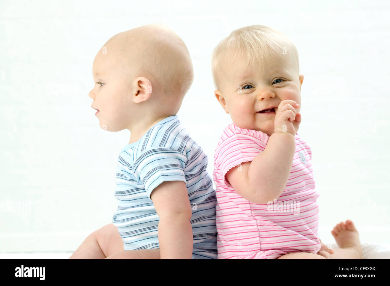 Deux Bebes Assis Dos A Dos Bebe Male A Gauche Wearing Blue Striped Babygro A Cote De Bebe De Sexe Feminin Sur Le Port De Droite Photo Stock Alamy