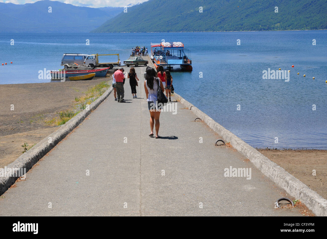 Les touristes et les habitants sur la jetée menant à une embarcation de plaisance et les petits bateaux, lac Villarrica, Araucania, au Chili. Banque D'Images