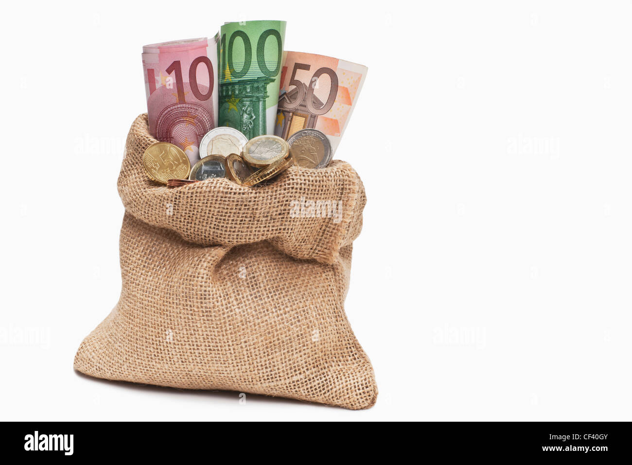 Viele Euro Banknoten und Münzen befinden sich in einem Jutesack. | beaucoup de l'introduction des billets et des pièces dans un sac de jute, arrière-plan blanc Banque D'Images