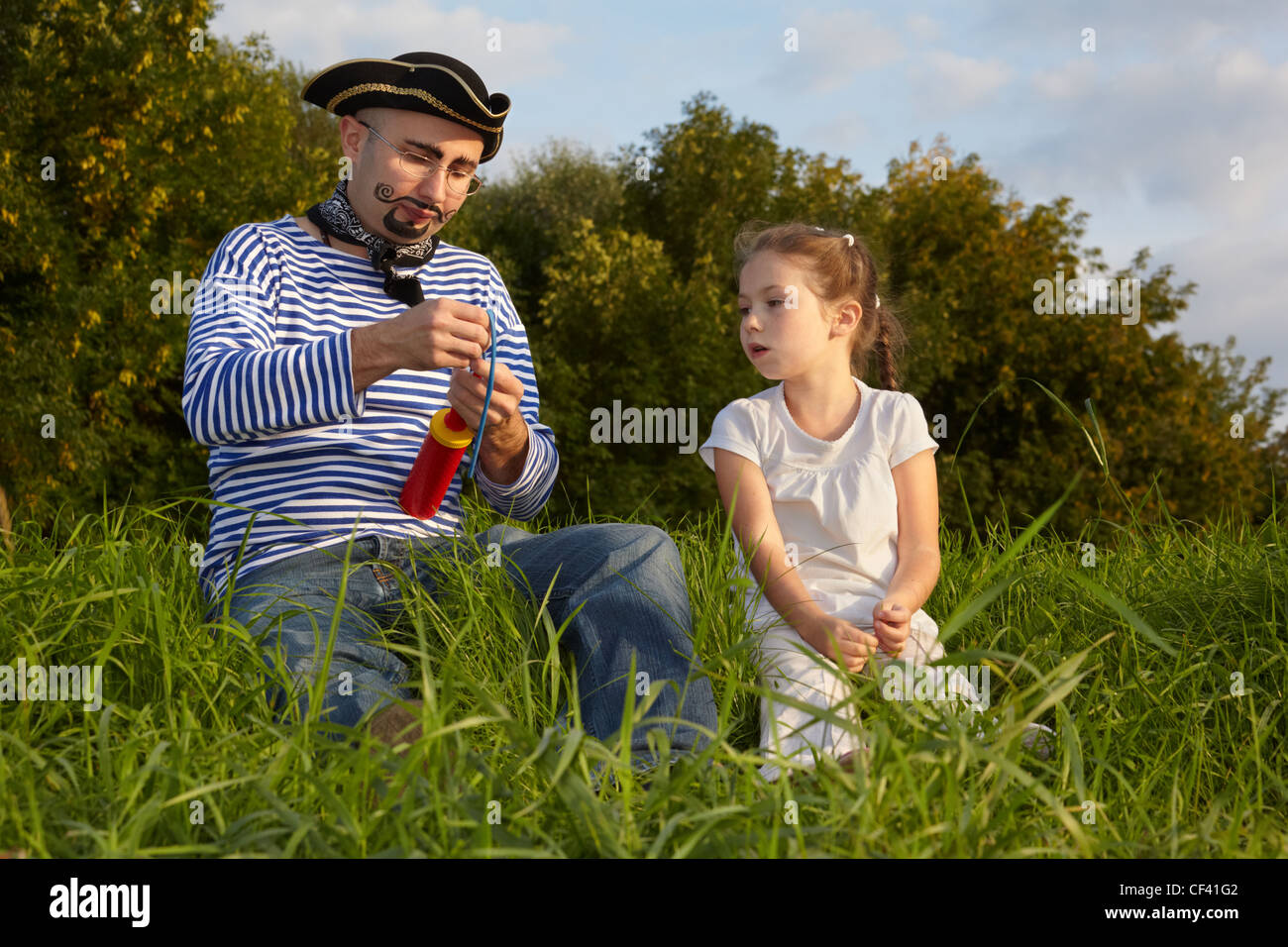 Papa en costume de pirate et la fille est assise sur l'herbe. père soyez prêt à gonfler montgolfière Banque D'Images