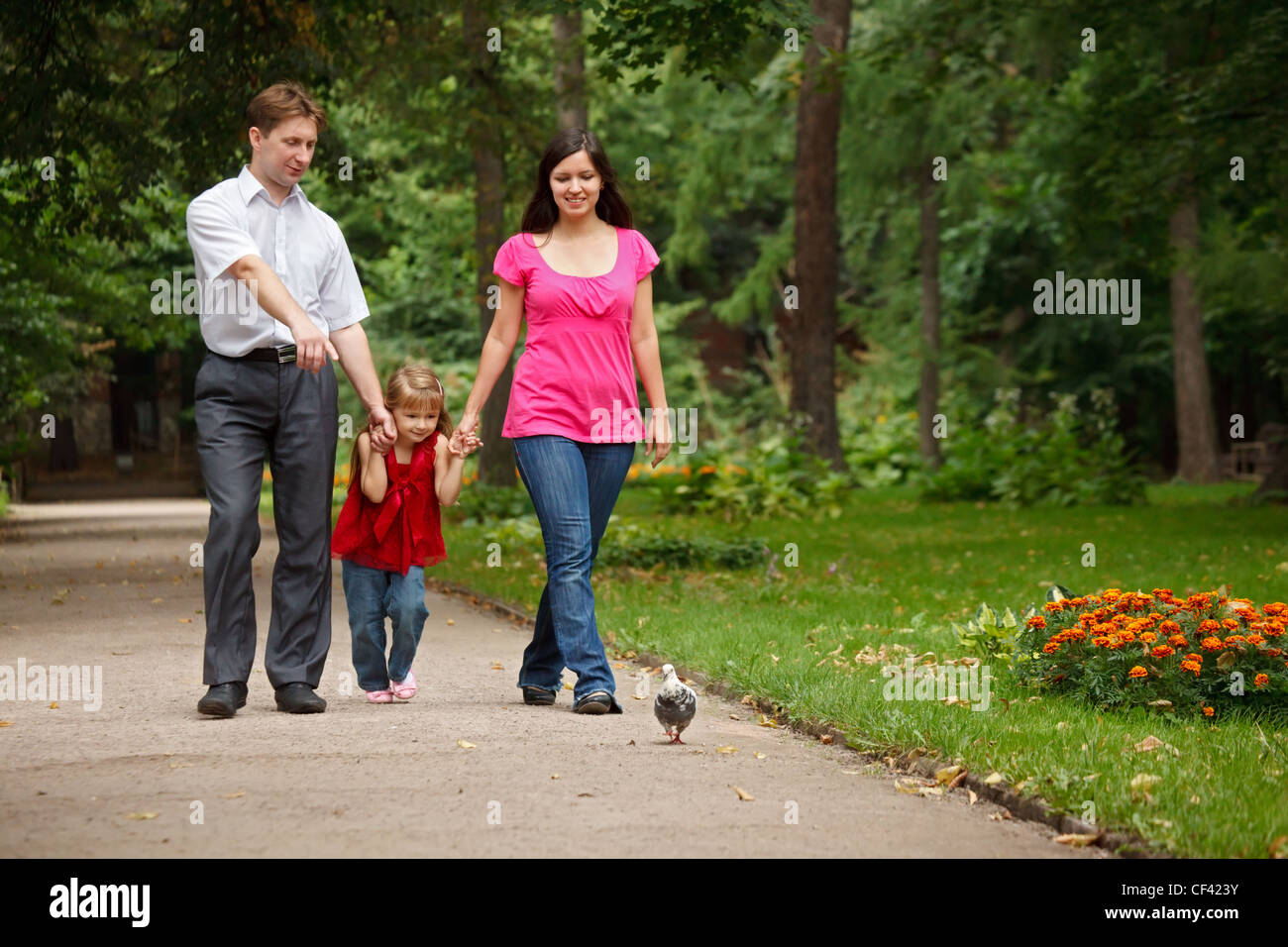 Les parents avec fille marcher sur jardin d'été. L'homme montre à la fille de pigeon. Banque D'Images