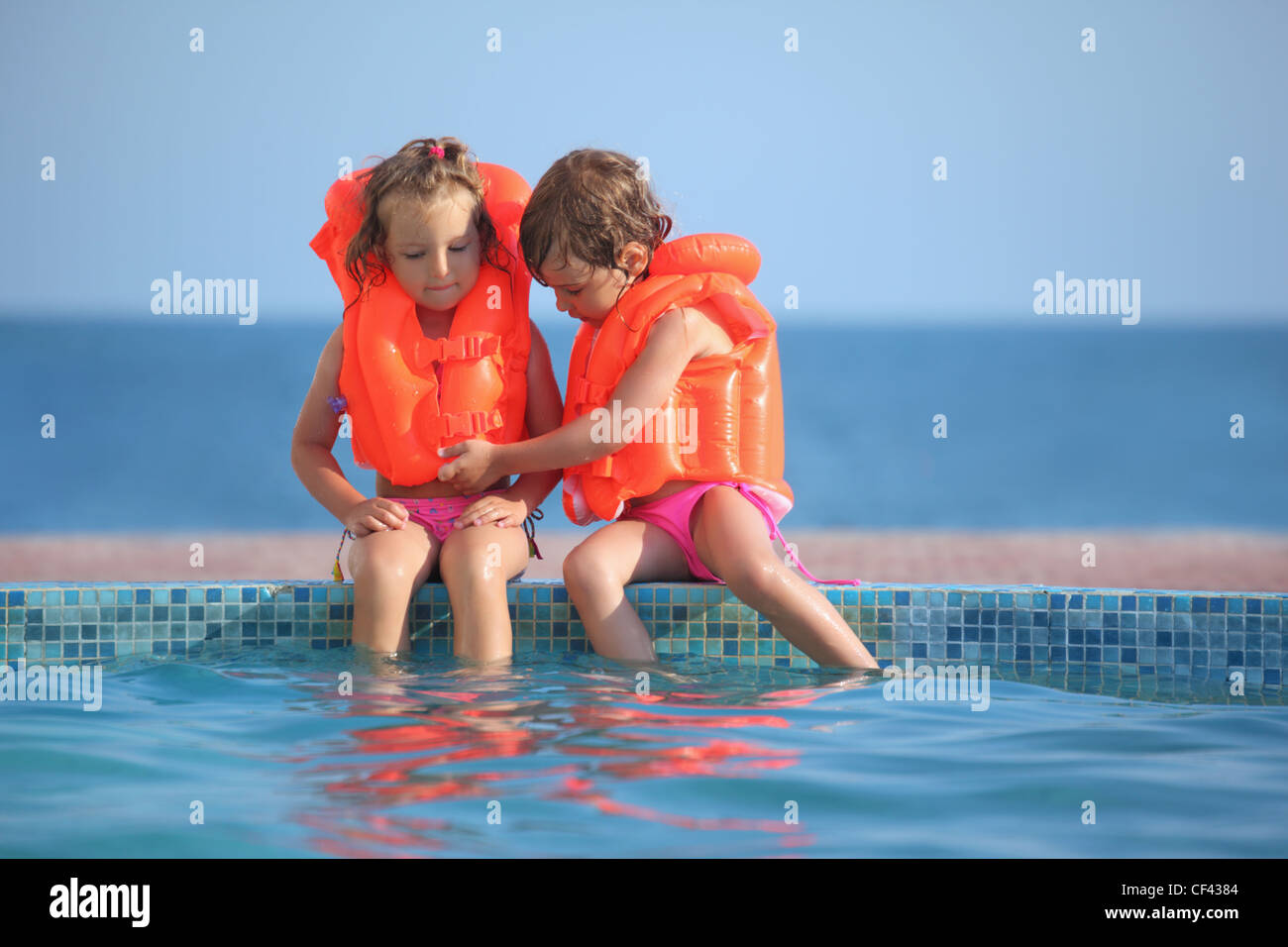 Deux petites filles en gilets assis sur ledge pool sur resort Photo Stock -  Alamy