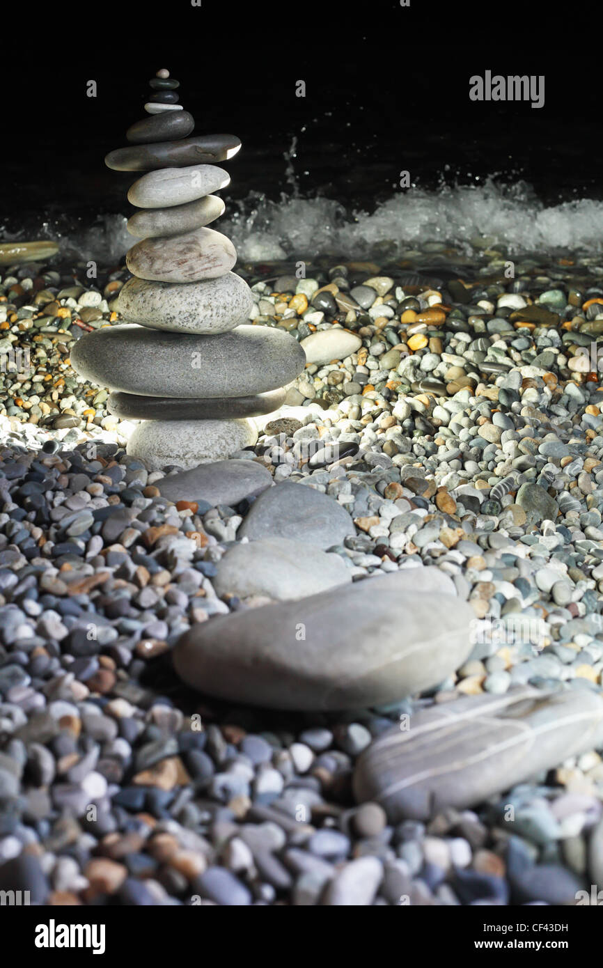 Pyramide du pebble sur le littoral rocailleux de nuit Banque D'Images