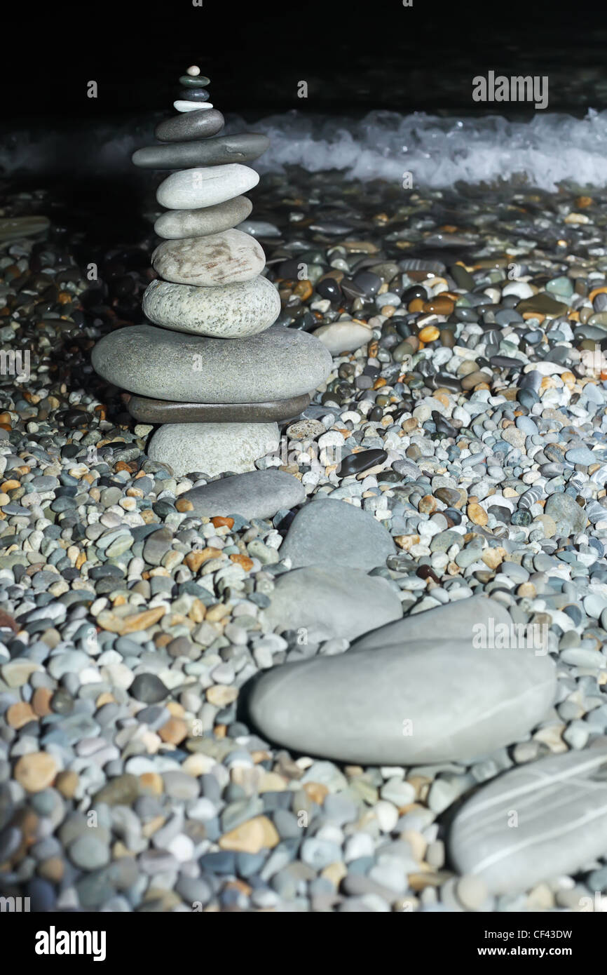 Pyramide du pebble sur le littoral rocailleux de nuit Banque D'Images