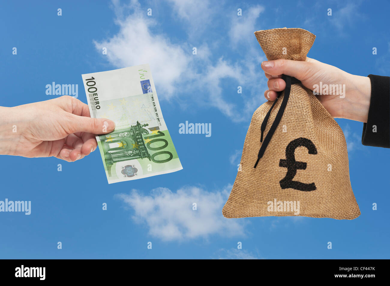 Une loi de 100 euros est tenue à la main. De l'autre côté d'un sac d'argent  avec une monnaie livre signe est tenue à la main Photo Stock - Alamy