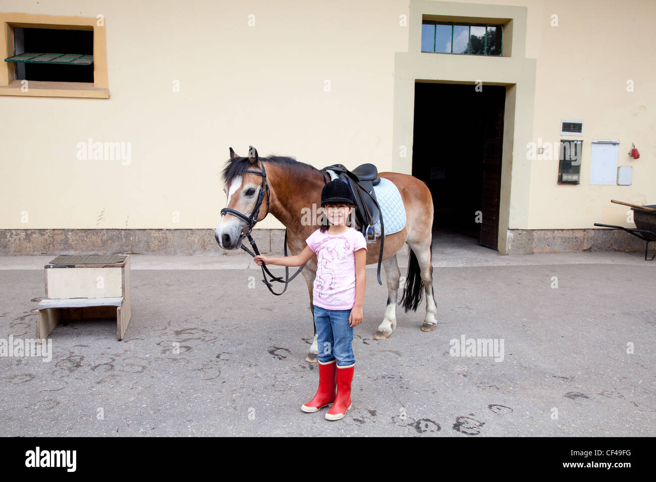 Petite fille debout à côté de son cheval prêt pour une leçon d'équitation. Banque D'Images