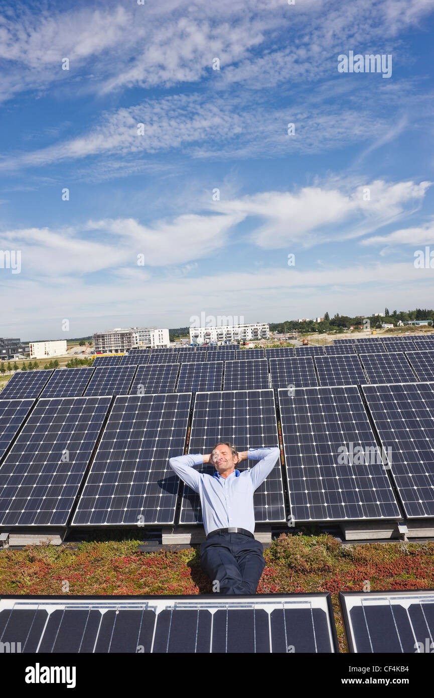 Allemagne, Munich, Mature man resting sur panneau en centrale solaire, smiling Banque D'Images