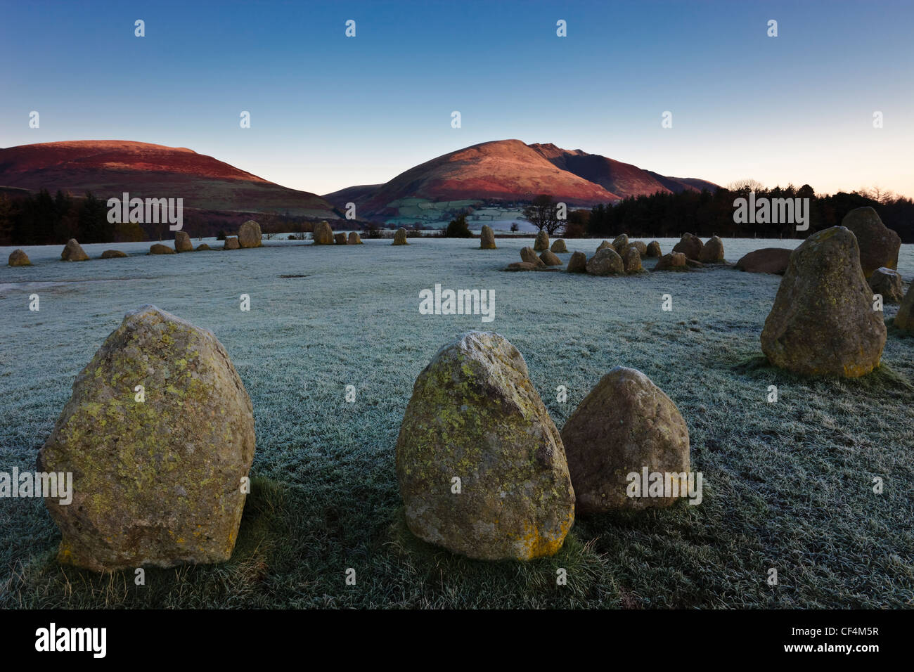 Sur un cercle de pierres de Castlerigg frosty matin tandis que les premiers rayons de lumière sur les pentes de Blencathra dans le Lake District. Banque D'Images