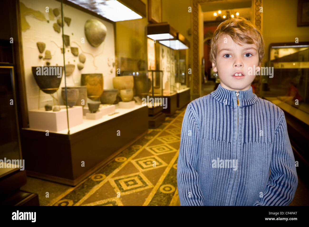 Excursion au garçon au musée historique près de pièces d'anciennes reliques dans des vitrines Banque D'Images