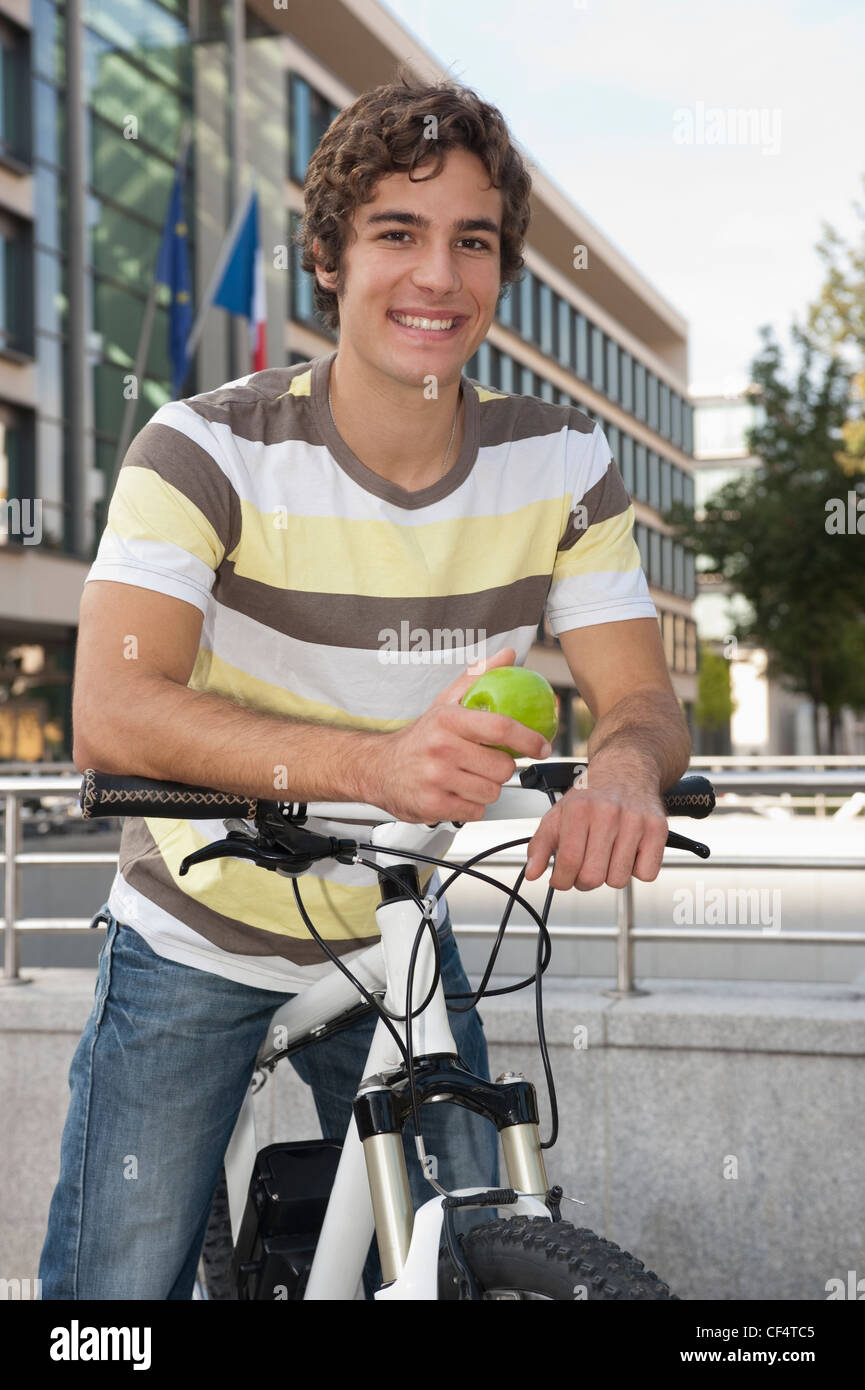 Allemagne, Bavière, jeune homme à bicyclette avec apple, smiling, portrait Banque D'Images