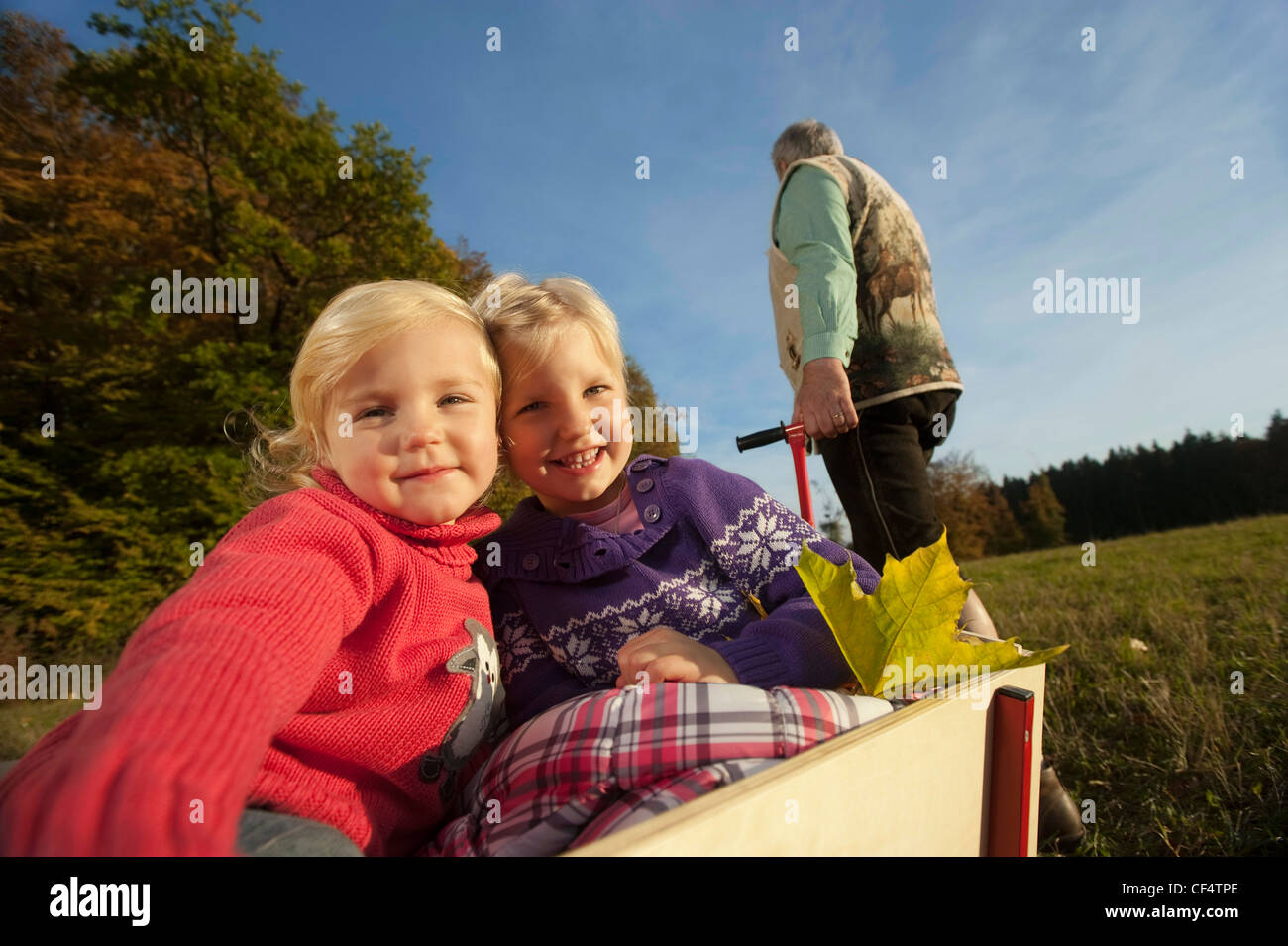 Allemagne, Bavière, grand-père tirant petites-filles assis dans wagon Banque D'Images