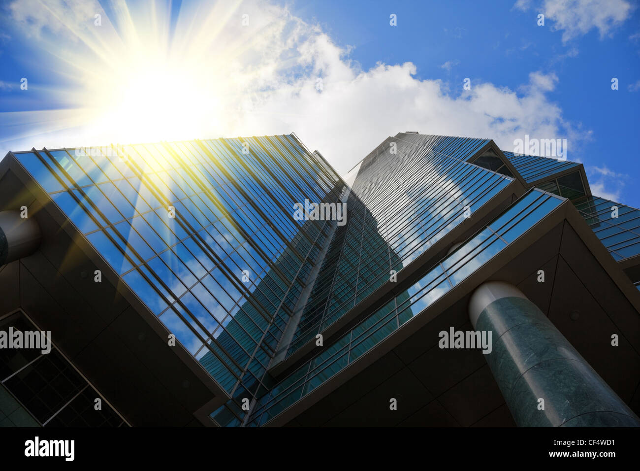 Immeuble de bureaux à miroir style high tech, ciel bleu avec des nuages reflétée à l'ici, rayons de soleil Banque D'Images