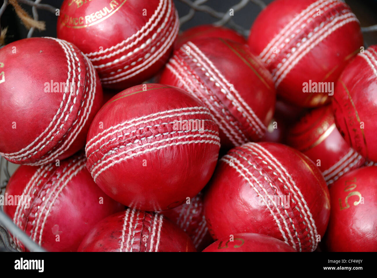 Un panier plein de vieux rouge cricket balls. Banque D'Images