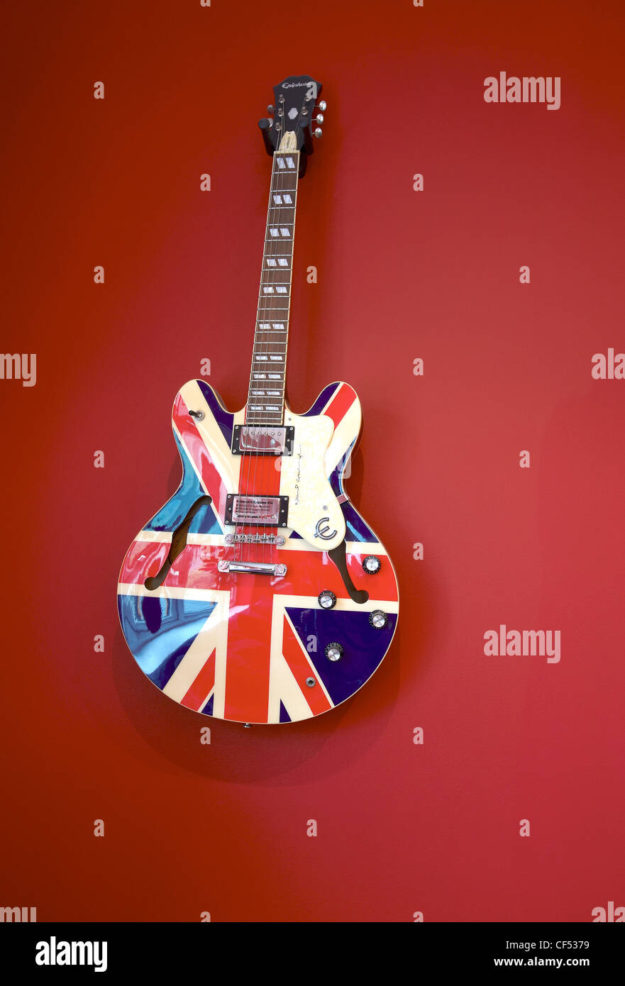 Un design Union jack guitare électrique affichée sur un mur rouge. Banque D'Images