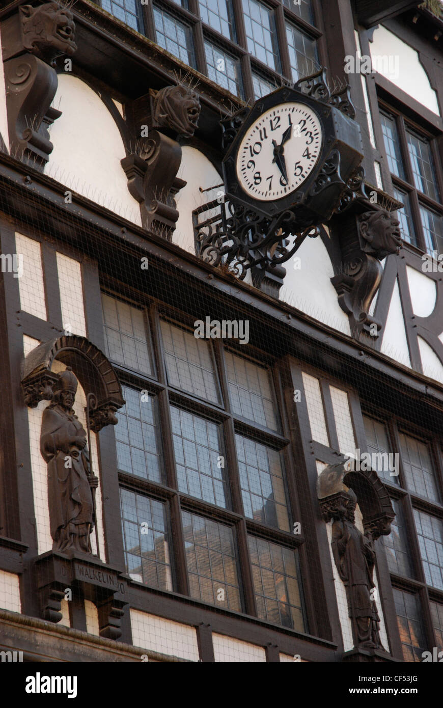 À la recherche jusqu'à un bâtiment tudor poutres montrant une horloge façade à Winchester. Banque D'Images