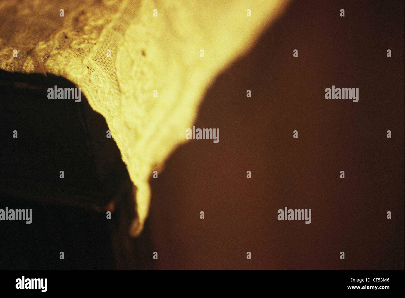 Close up detail d'une dentelle dans des tons chauds de jaune et or avec couleur de fond brun Banque D'Images