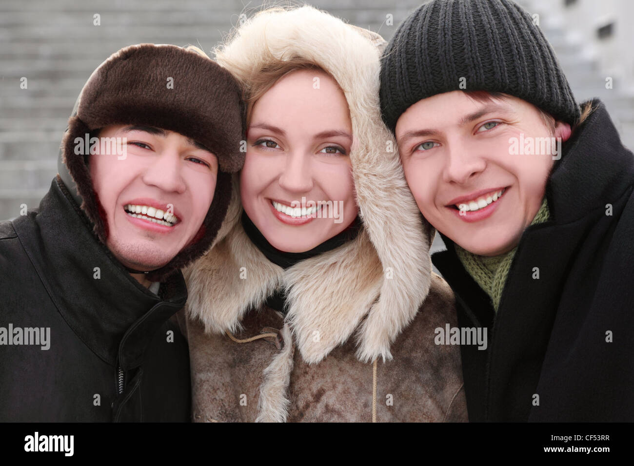 Trois amis smiling and looking at camera, moitié du corps, journée d'hiver, les escaliers d'arrière-plan Banque D'Images