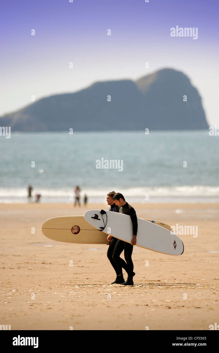 Les surfeurs le sable à Rhossili Bay sur la Gower, S. Wales (23 mai 2009). Banque D'Images