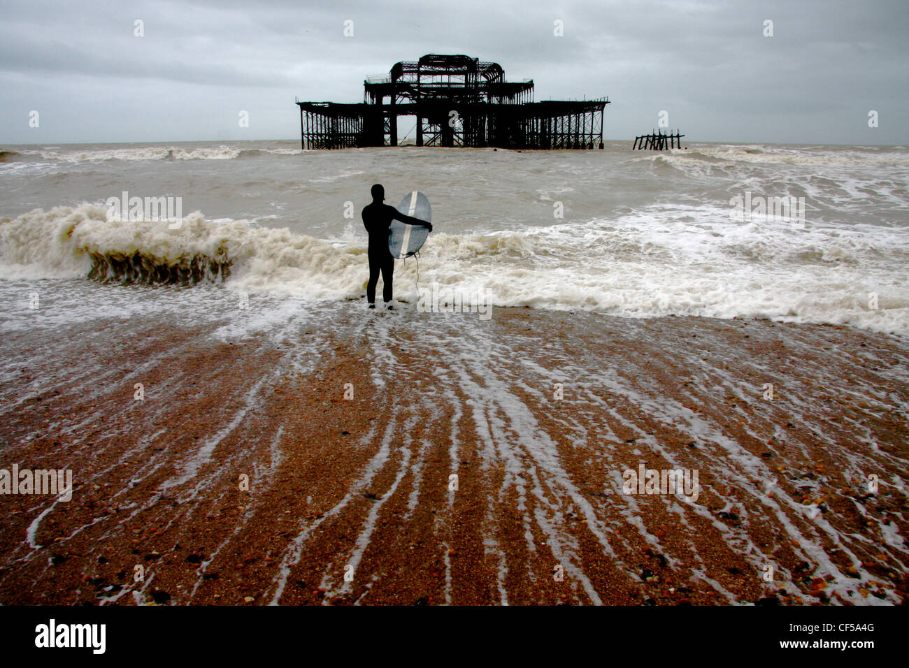 Surfeur SUR PLAGE, EN FACE DE L'Old West Pier de Brighton, UK Banque D'Images