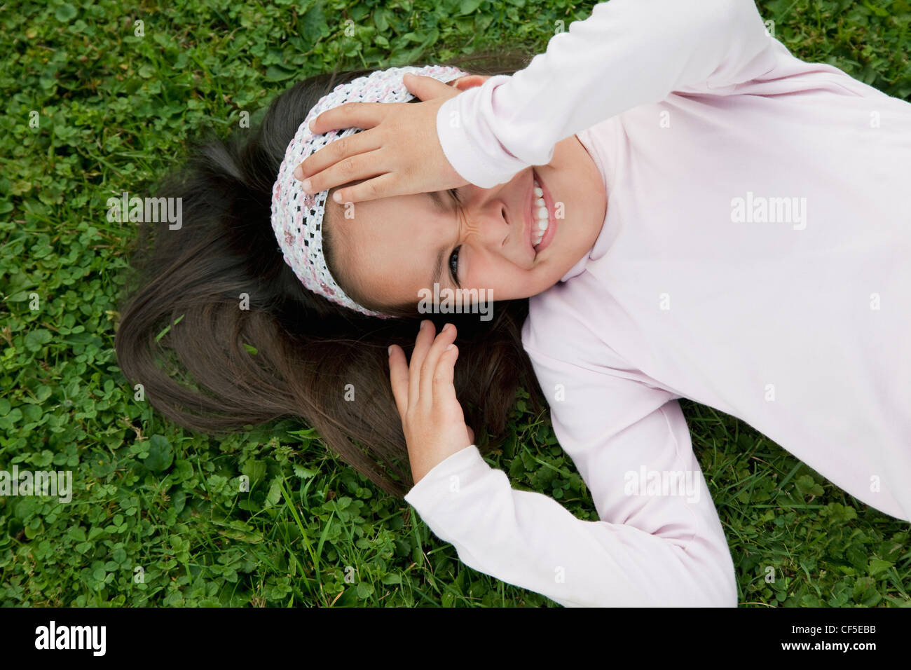 Allemagne, Bavière, Huglfing, Girl lying on grass in garden, smiling, portrait Banque D'Images