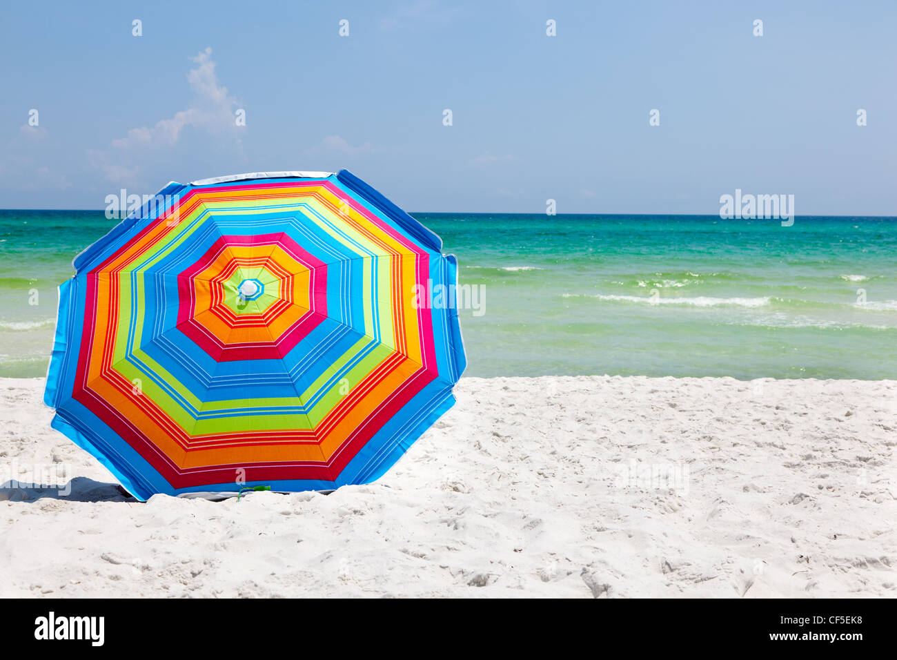 Parapluie coloré assis sur une plage de sable fin avec l'océan et de ciel bleu en arrière-plan Banque D'Images