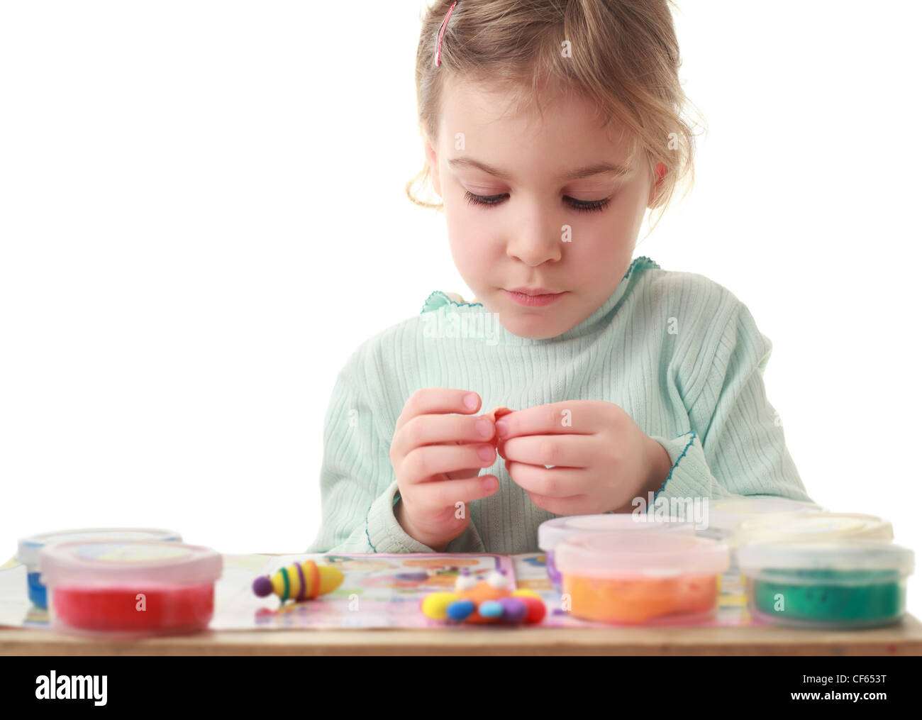 Petite fille assise à table et sculpte soigneusement de pâte à modeler rend les chiffres Banque D'Images