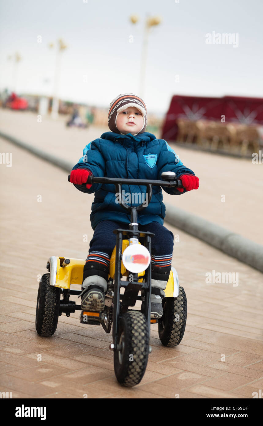 Little Boy riding tricycle dans une froide journée d'hiver Banque D'Images