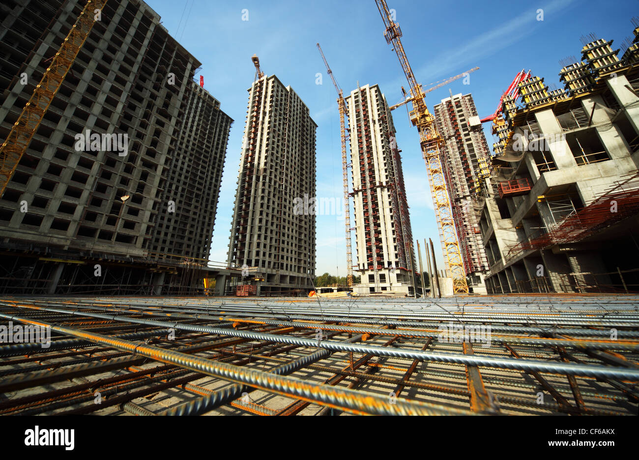 Entre de grands bâtiments en construction et les grues sous un ciel bleu Banque D'Images