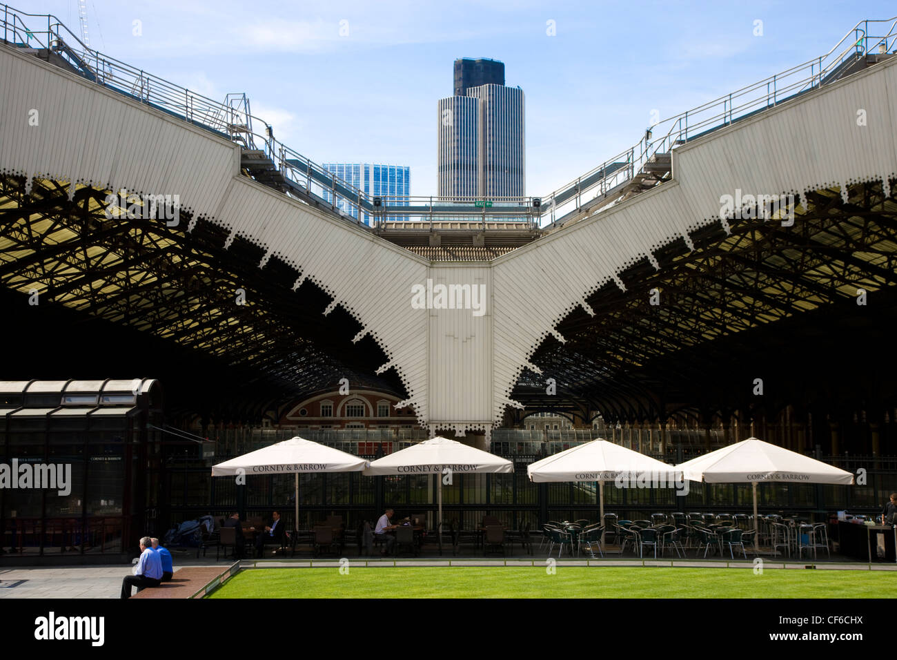 Une rangée de tables de café sous de grands parasols dans Broadgate à l'arrière de la gare de Liverpool Street. Banque D'Images