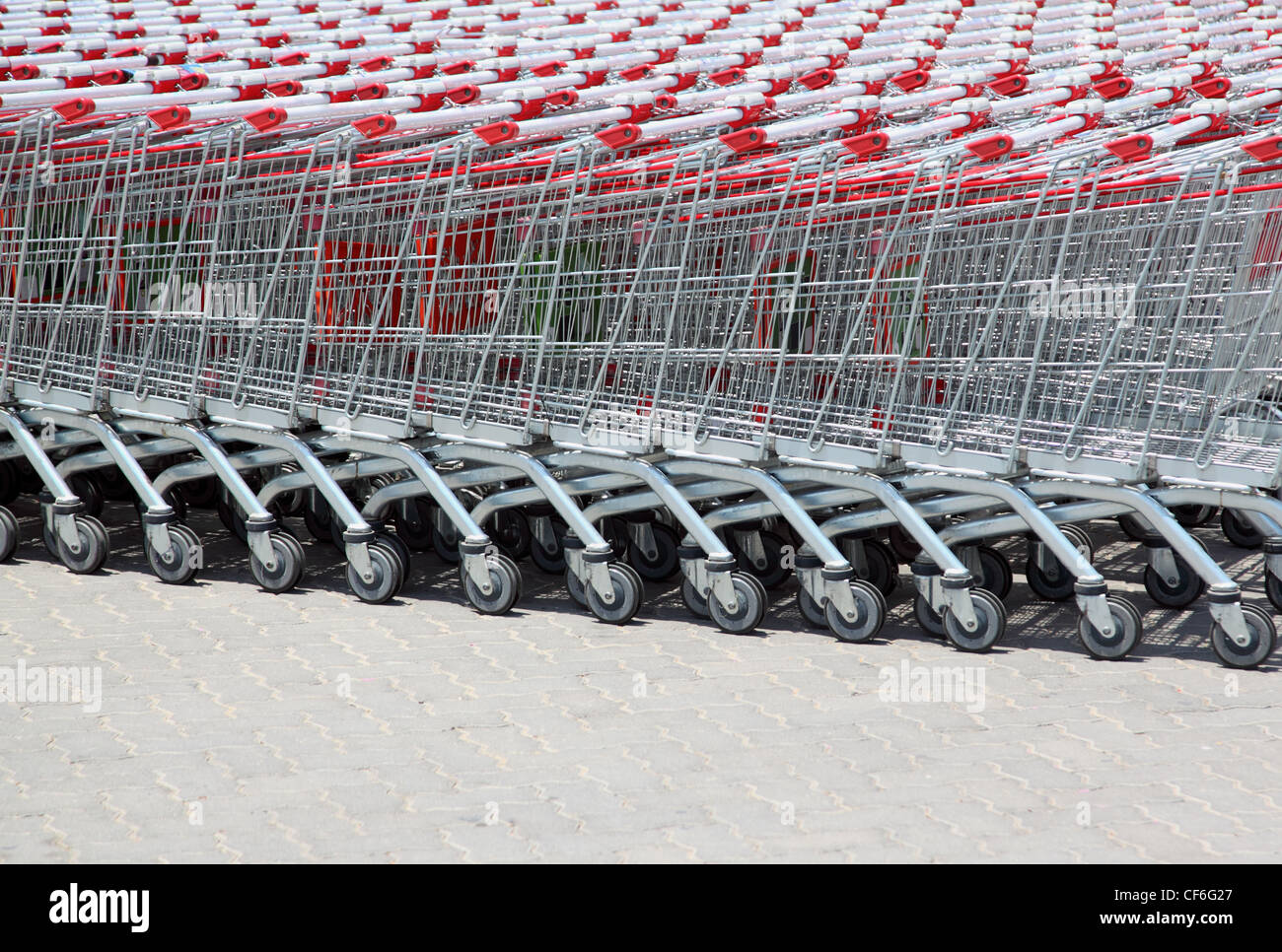Série de chariots de supermarché empilés avec poignée rouge hors des portes Banque D'Images