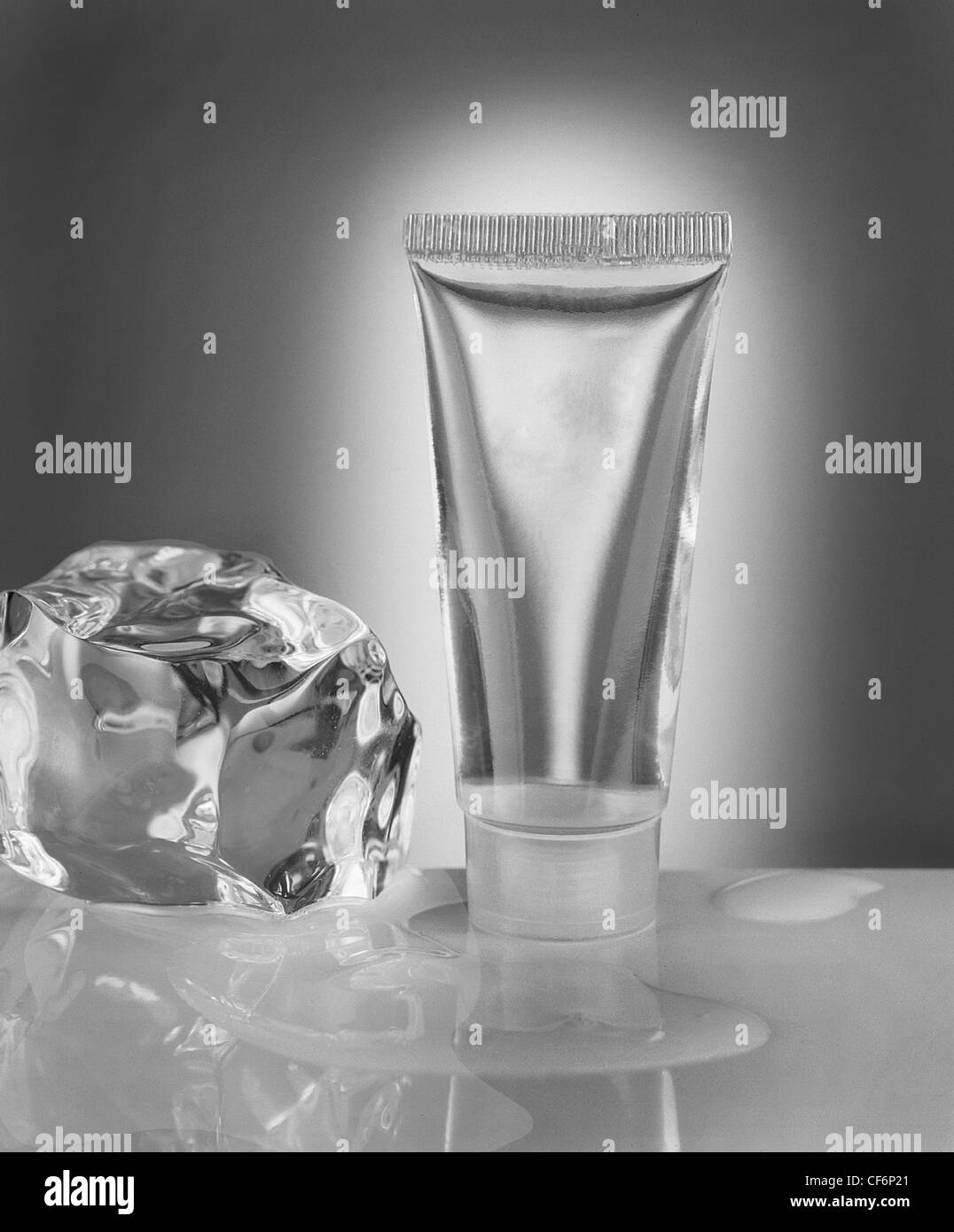 Photographie conceptuelle du tube cosmétique de sérum transparent avec cube de glace et eau. Image monochromatique Banque D'Images